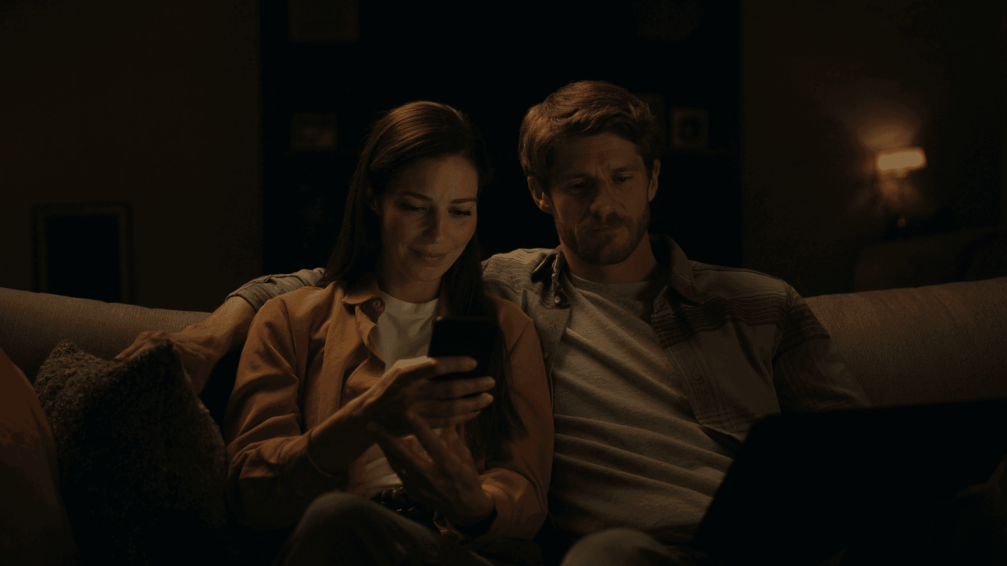 Two partners reviewing finances together from a couch at night.